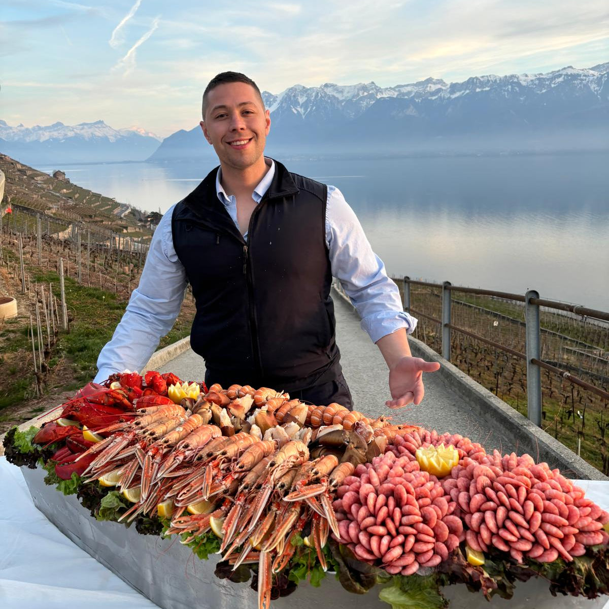 A member of the Fiskskaldjur team with a large platter of Swedish seafood above Lake Geneva