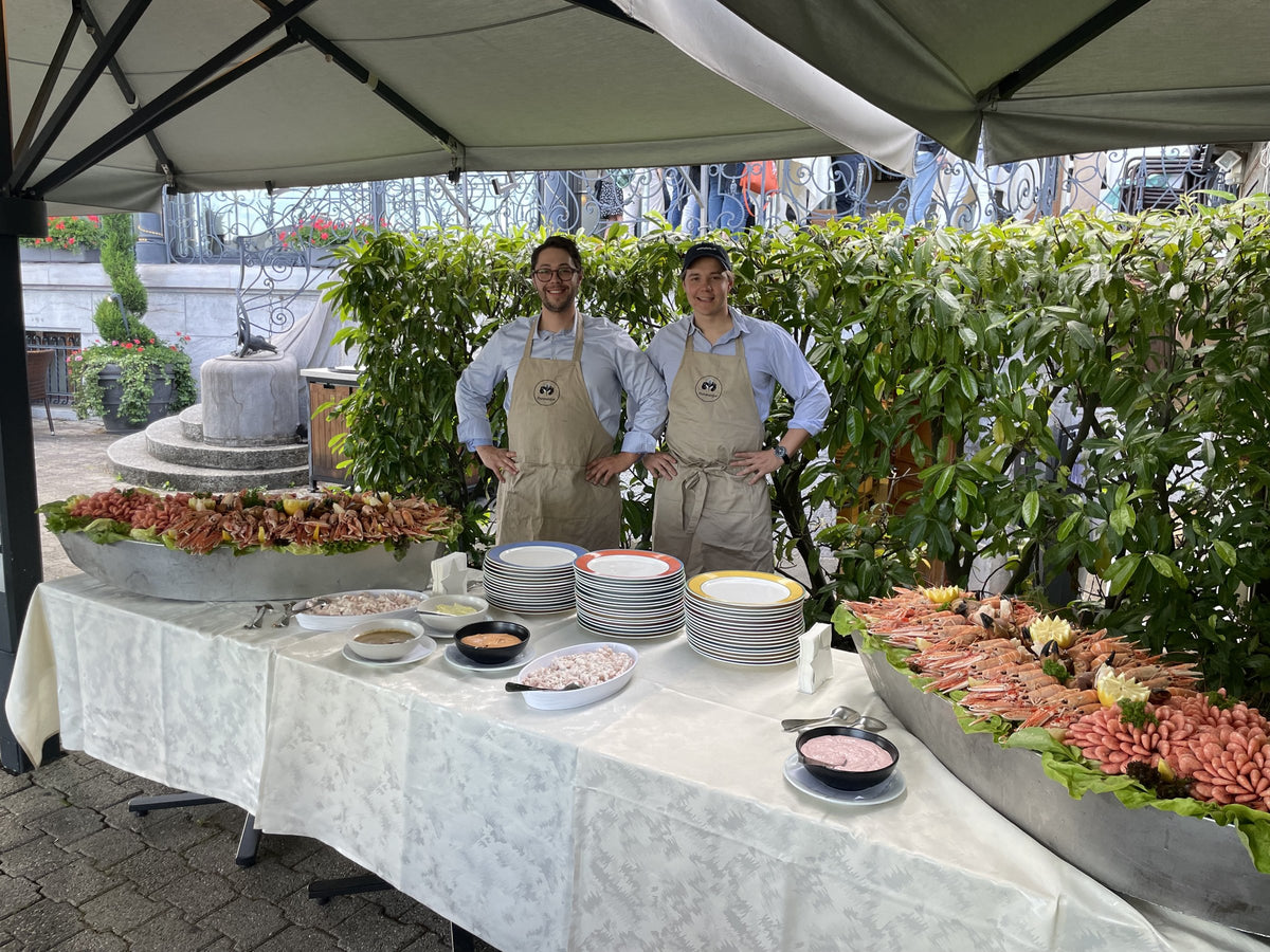 Deux membres de l’équipe Fiskskaldjur derrière un buffet de fruits de mer sous une tente de jardin